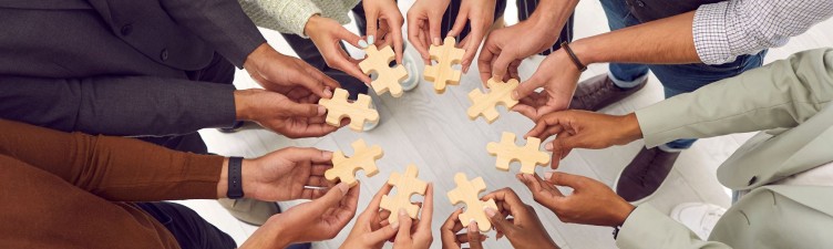 Diverse team members holding puzzle pieces in a circle